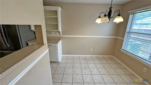 601 Barber Dr, Copperas Cove, TX 76522 - unfurnished dining area featuring a chandelier, light tile patterned flooring, and baseboards