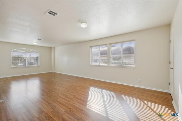unfurnished living room featuring healthy amount of natural light, wood finished floors, and baseboards