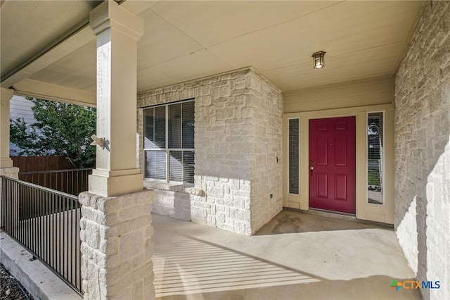 view of exterior entry featuring covered porch and stone siding