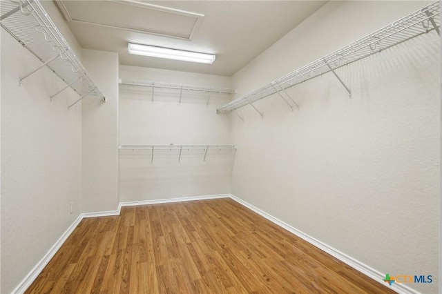 spacious closet with wood finished floors and attic access