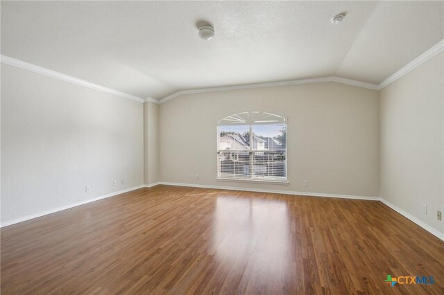 spare room with lofted ceiling, ornamental molding, wood finished floors, baseboards, and a smoke detector