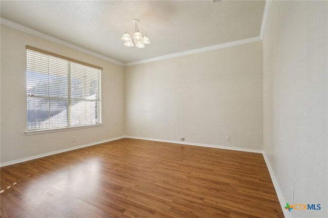 spare room with a chandelier, crown molding, wood finished floors, and baseboards
