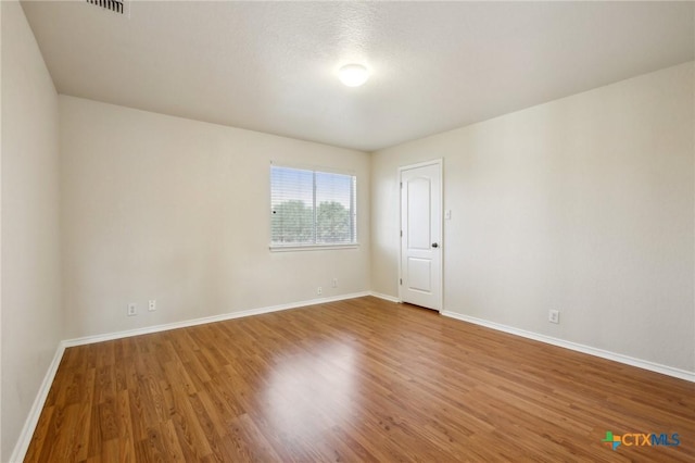 spare room featuring wood finished floors and baseboards