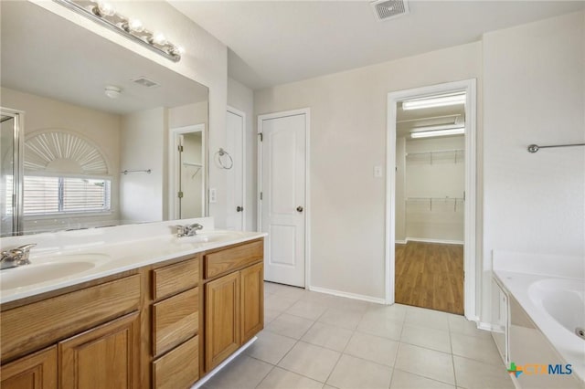 full bathroom featuring tile patterned floors, a garden tub, double vanity, and baseboards