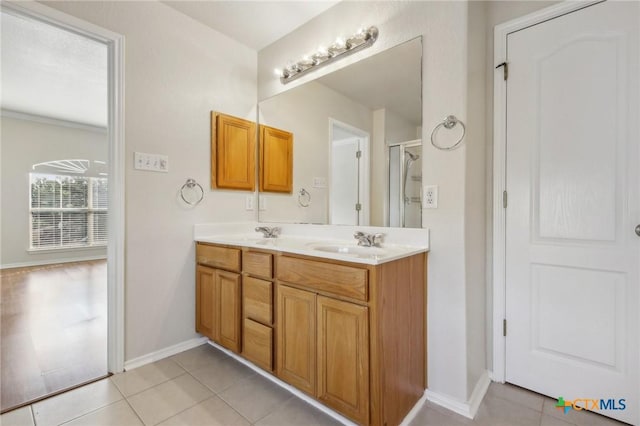 bathroom featuring tile patterned flooring, double vanity, baseboards, and an enclosed shower