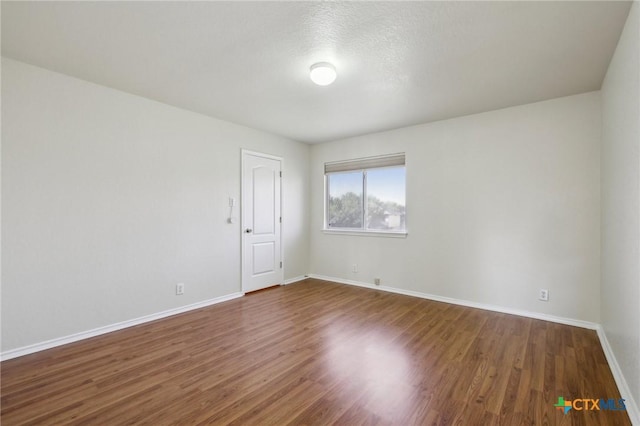 empty room with baseboards and dark wood-style floors
