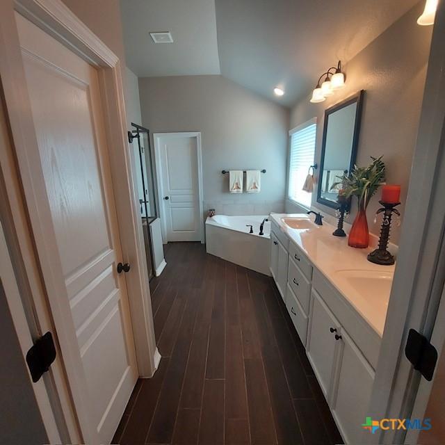 1802 Rustic Manor Dr, Temple, TX 76502 - bathroom with wood finished floors, lofted ceiling, a bath, and double vanity