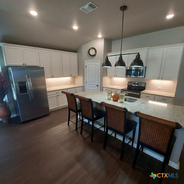 1802 Rustic Manor Dr, Temple, TX 76502 - kitchen featuring appliances with stainless steel finishes, a breakfast bar area, dark wood-style flooring, white cabinetry, and pendant lighting