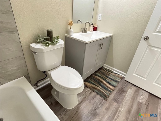 708 E 5th St, Nixon, TX 78140 - full bath featuring a textured wall, wood finished floors, vanity, and a bathtub