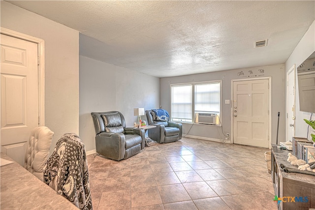 living area with cooling unit, a textured ceiling, and light tile patterned flooring