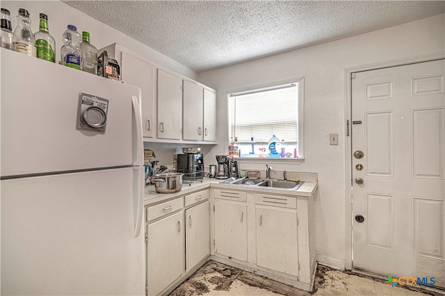 kitchen with white cabinetry, a textured ceiling, sink, and white fridge