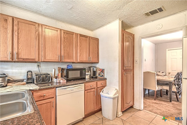 kitchen featuring dishwasher, a textured ceiling, sink, and light tile patterned flooring