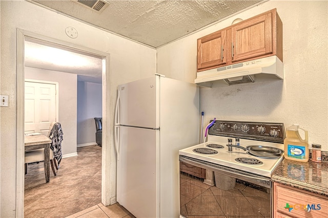 kitchen featuring dark stone counters, white appliances, and light tile patterned floors