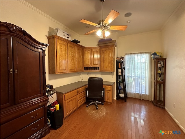 office space featuring built in desk, ceiling fan, crown molding, and hardwood / wood-style flooring