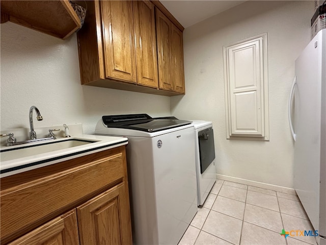 washroom featuring cabinets, sink, light tile patterned floors, and separate washer and dryer