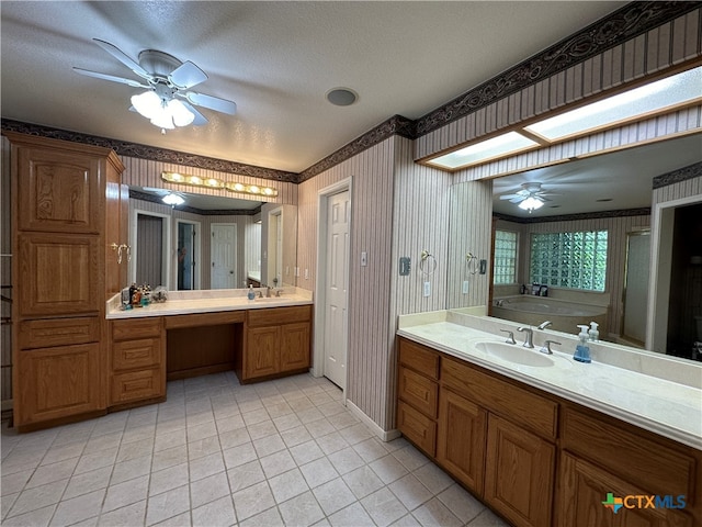 bathroom with tile patterned flooring, a textured ceiling, a bathtub, ceiling fan, and a skylight