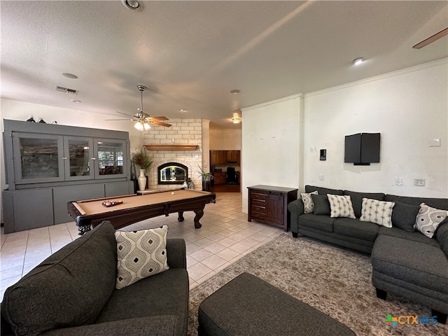 living room with pool table, a textured ceiling, light tile patterned flooring, ceiling fan, and a fireplace