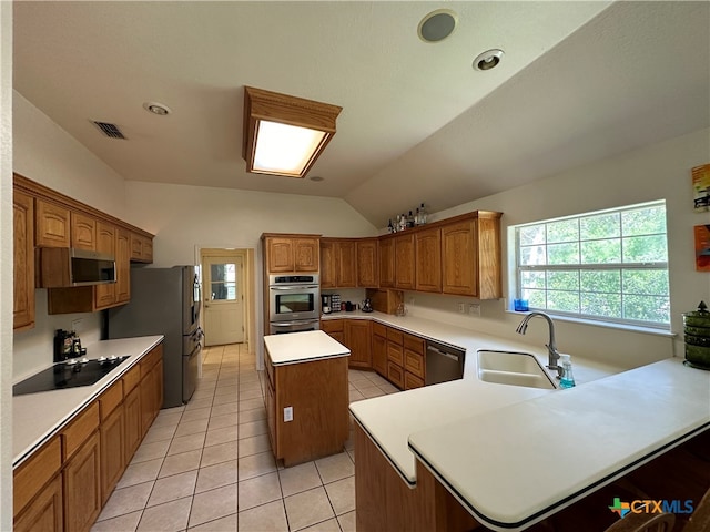 kitchen featuring stainless steel appliances, vaulted ceiling, sink, light tile patterned floors, and a kitchen island