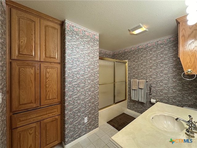 bathroom featuring vanity, bath / shower combo with glass door, a textured ceiling, and tile patterned floors