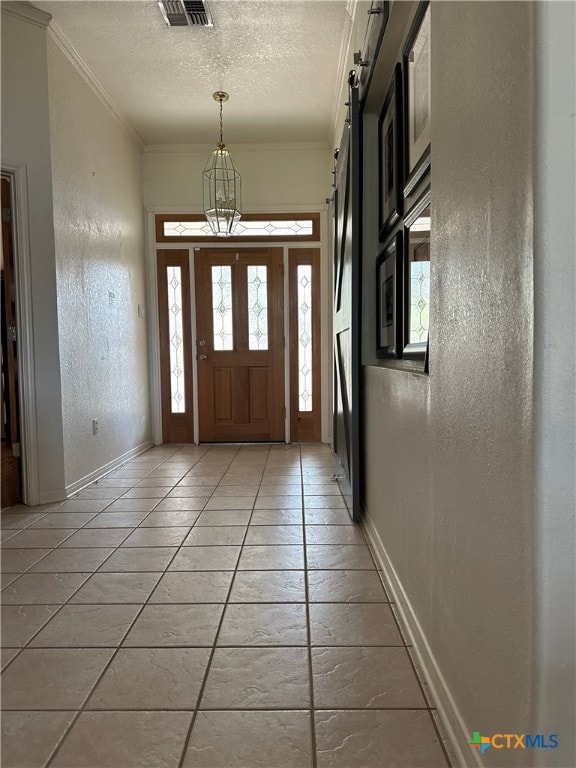 tiled entrance foyer featuring a barn door and crown molding