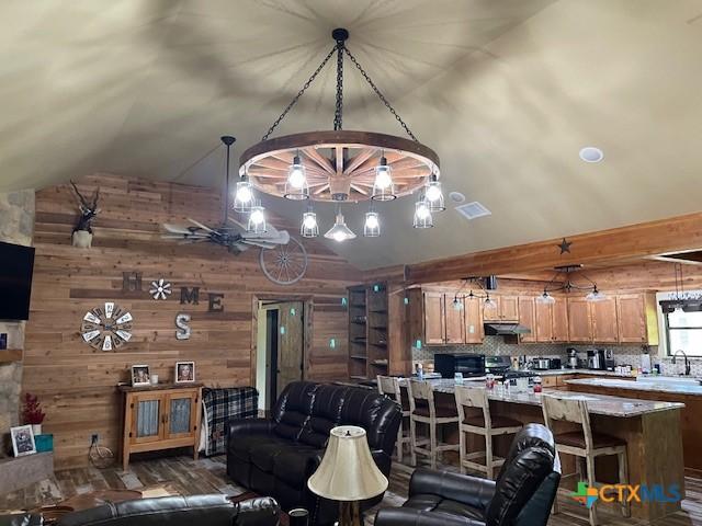 2357 Myrtle Ln, Cameron, TX 76520 - living area with vaulted ceiling, wood walls, a chandelier, and dark wood finished floors