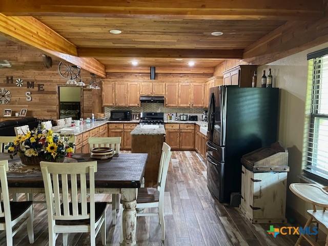 2357 Myrtle Ln, Cameron, TX 76520 - kitchen with black appliances, under cabinet range hood, beam ceiling, hardwood / wood-style flooring, and light countertops