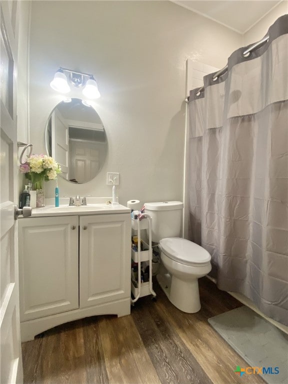 bathroom with hardwood / wood-style floors, toilet, vanity, and a shower with shower curtain