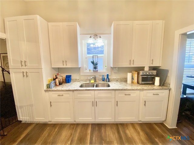 kitchen with sink, dark wood-type flooring, white cabinetry, and light stone countertops