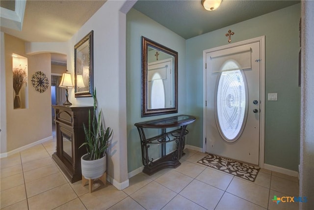 entrance foyer featuring arched walkways, baseboards, and light tile patterned floors