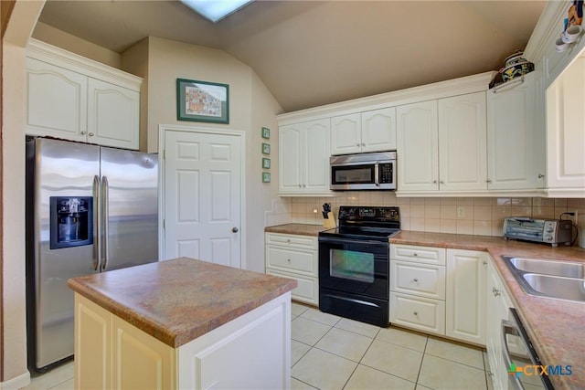 kitchen with backsplash, vaulted ceiling, light tile patterned flooring, appliances with stainless steel finishes, and white cabinetry