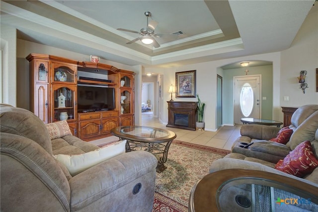 living room with a tray ceiling, light tile patterned flooring, baseboards, visible vents, and a ceiling fan