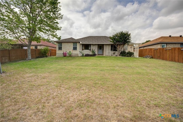 rear view of property featuring a fenced backyard and a lawn