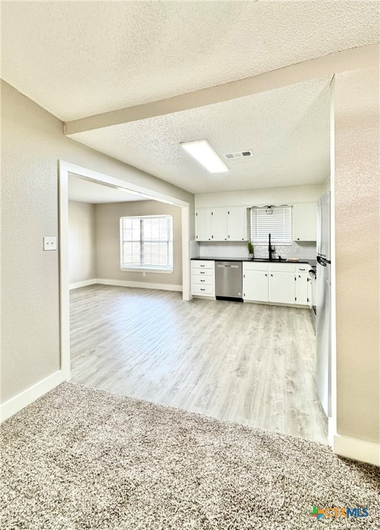 kitchen with stainless steel appliances, white cabinetry, light wood-type flooring, a textured ceiling, and sink