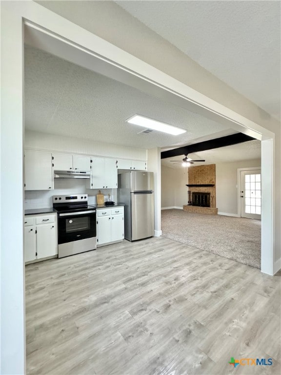 kitchen with stainless steel appliances, light hardwood / wood-style floors, ceiling fan, a fireplace, and white cabinets