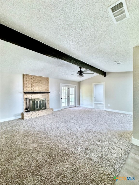 unfurnished living room with carpet flooring, a brick fireplace, a textured ceiling, and beam ceiling