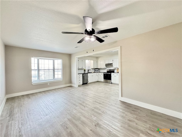 unfurnished living room with ceiling fan, sink, light hardwood / wood-style floors, and a textured ceiling