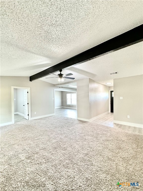 spare room with light colored carpet, a textured ceiling, ceiling fan, and beam ceiling