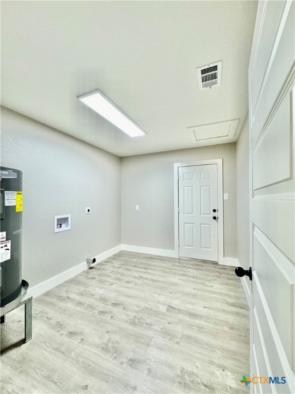 clothes washing area with washer hookup, water heater, and light hardwood / wood-style flooring