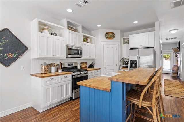 kitchen with visible vents, wood counters, appliances with stainless steel finishes, open shelves, and a sink