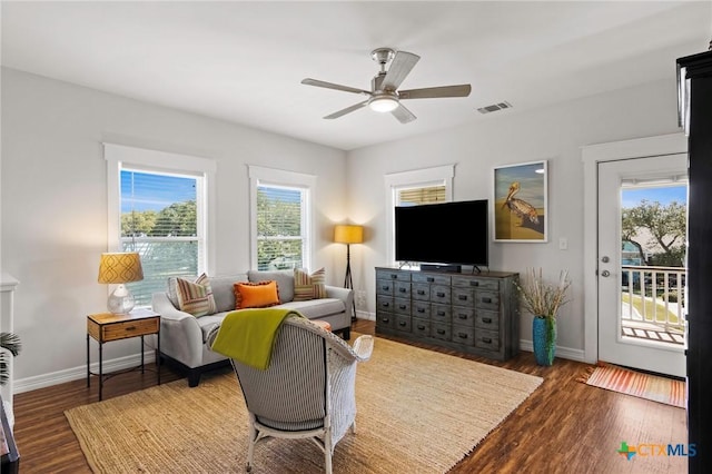 living area with a ceiling fan, wood finished floors, visible vents, and baseboards