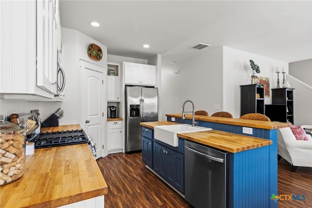 kitchen with visible vents, butcher block counters, appliances with stainless steel finishes, blue cabinets, and a sink