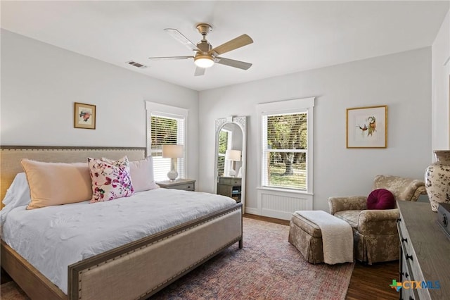 bedroom with a ceiling fan, visible vents, and wood finished floors