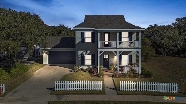 traditional-style home with a porch, a shingled roof, a balcony, a garage, and driveway