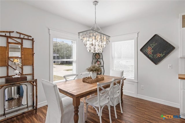 dining space with dark wood-type flooring, baseboards, and an inviting chandelier