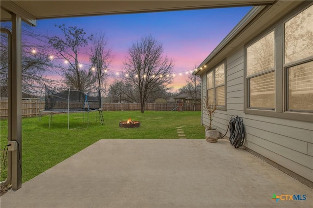 patio terrace at dusk with a lawn and an outdoor fire pit