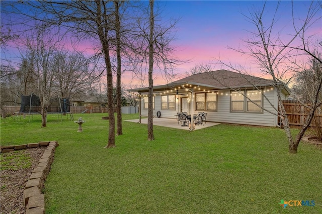 yard at dusk with a trampoline and a patio area