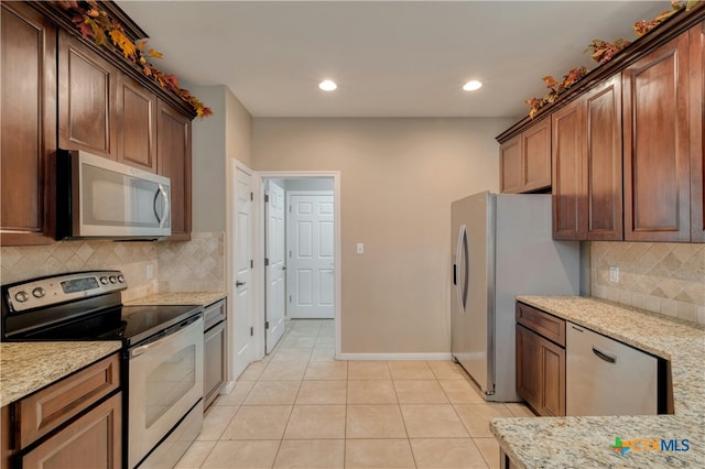 kitchen with light stone counters, tasteful backsplash, light tile patterned flooring, and appliances with stainless steel finishes