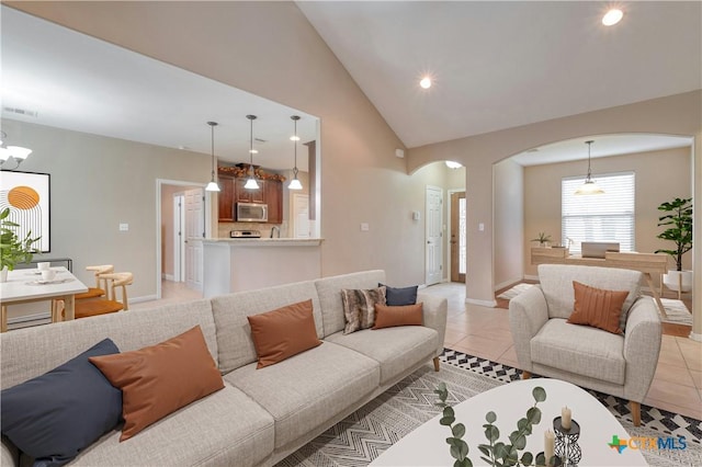 tiled living room with high vaulted ceiling and a notable chandelier