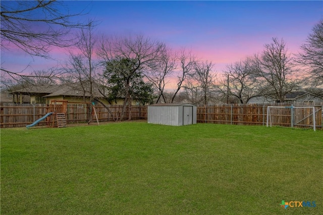 yard at dusk with a playground and a storage unit