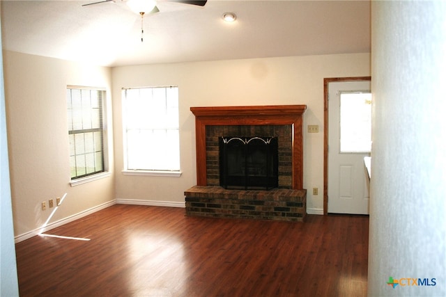 unfurnished living room with ceiling fan, dark wood-type flooring, and a brick fireplace